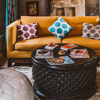 A living room with a sofa with 3 pillows and a coffee table with magazines on top