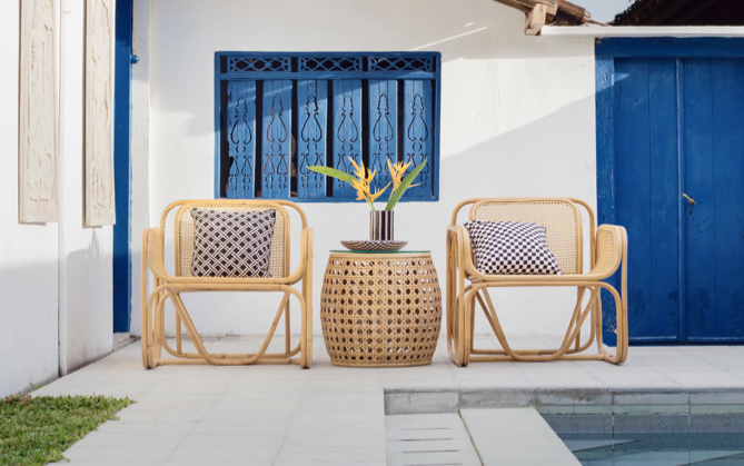 Two lawn chairs with blue pillows and a table with a plant in between the two chairs